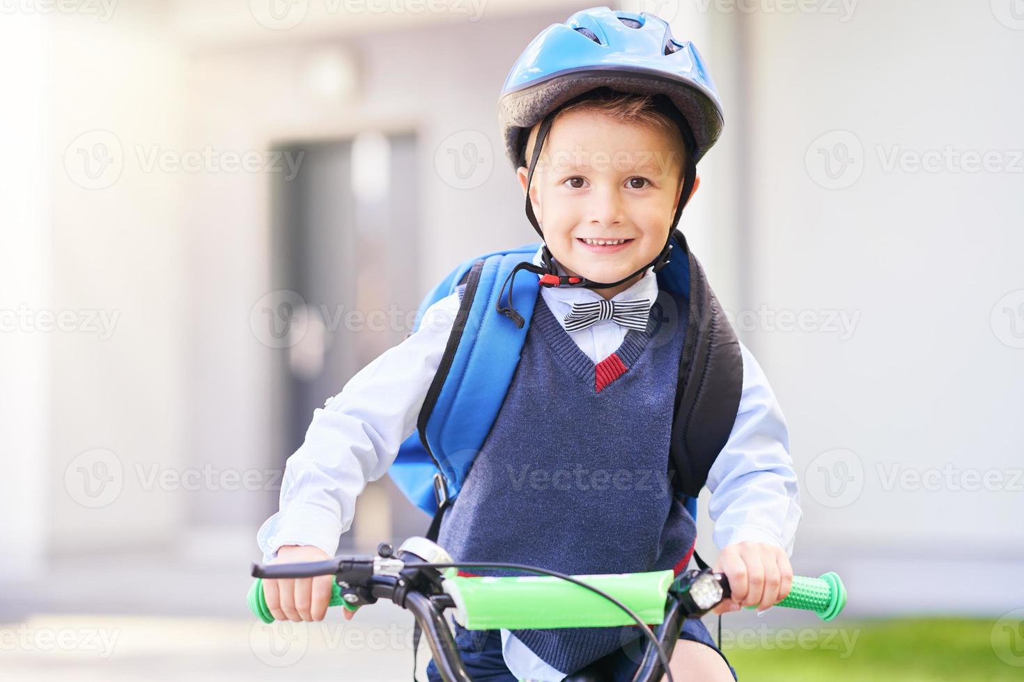 schuljunge im schutzhelm, der fahrrad mit rucksack fährt foto