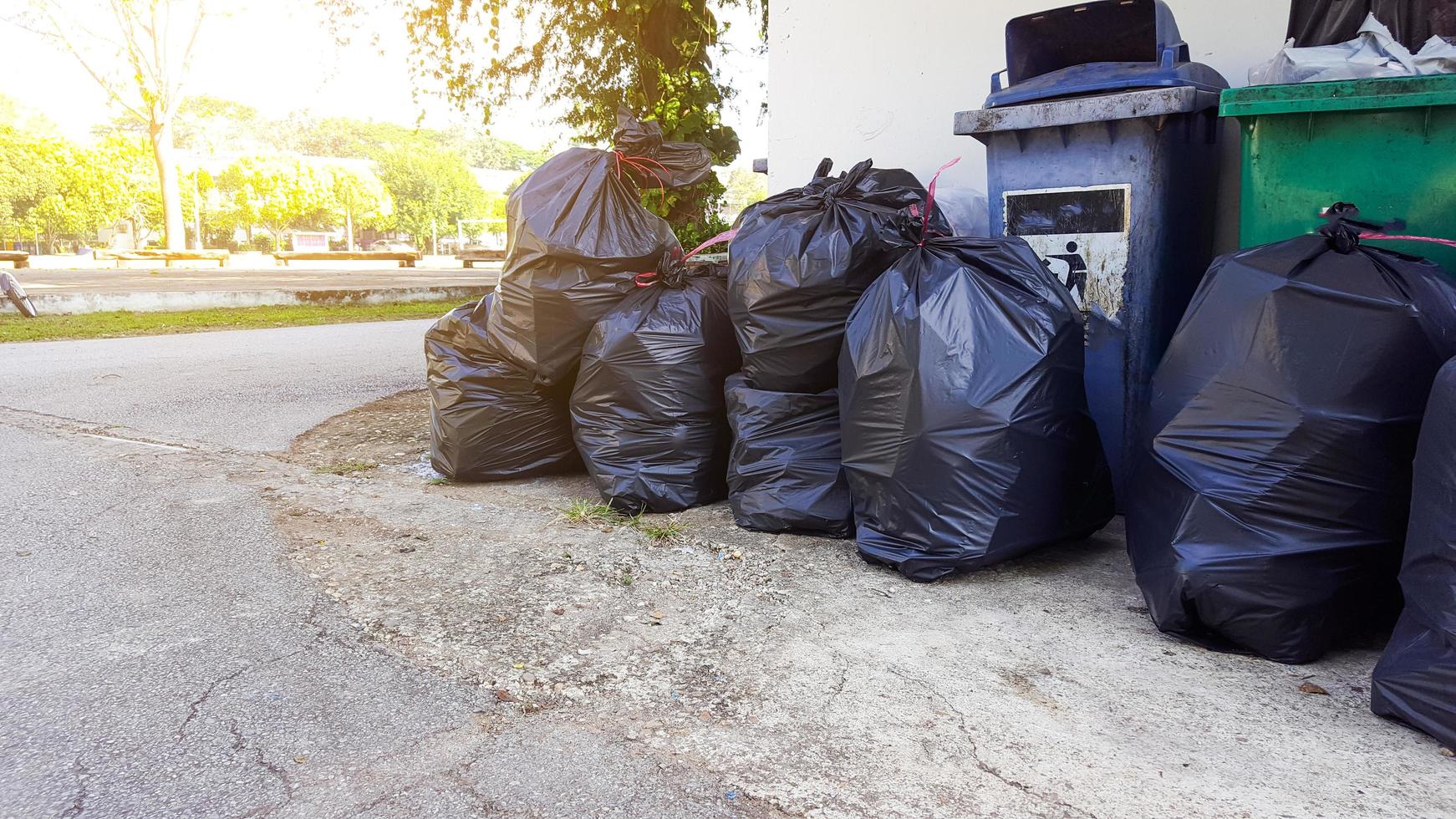 schwarze Plastikmüllsäcke auf dem Boden, die auf Recycling warten foto