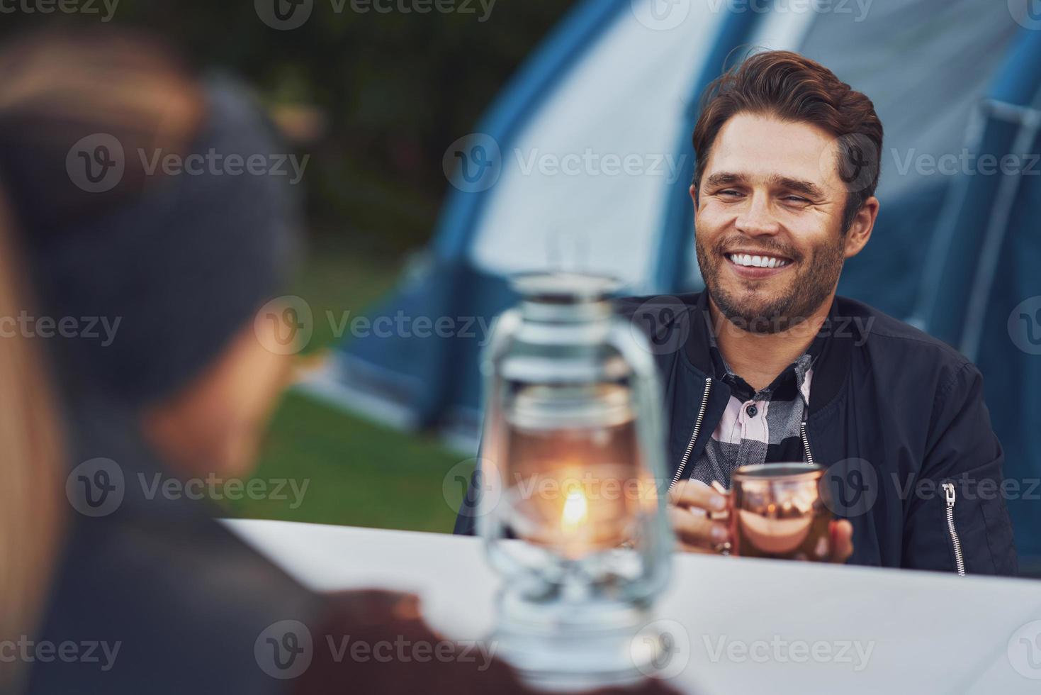 Junges nettes Paar, das sich beim Camping mit Petroleumlampe amüsiert foto