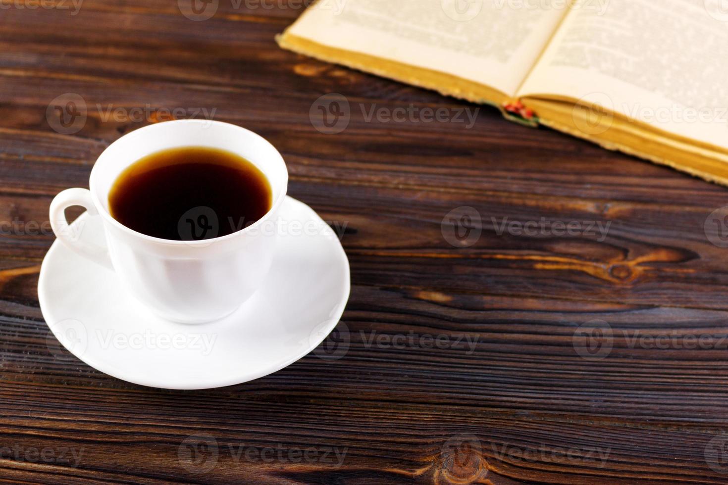 Stillleben mit Tasse Kaffee und Buch auf Grunge-Holztisch im Vintage-Stil foto