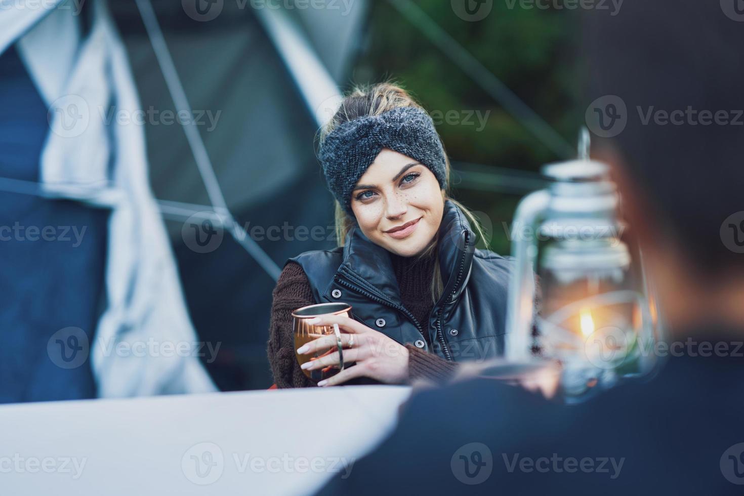 Junges nettes Paar, das sich beim Camping mit Petroleumlampe amüsiert foto