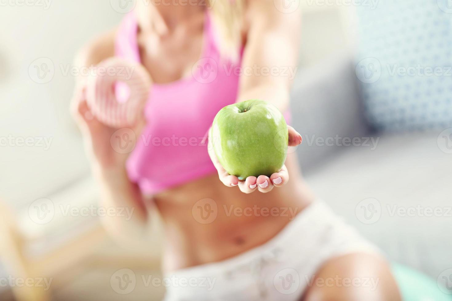 sportliche Frau mit Apfel und Donut nach dem Training foto