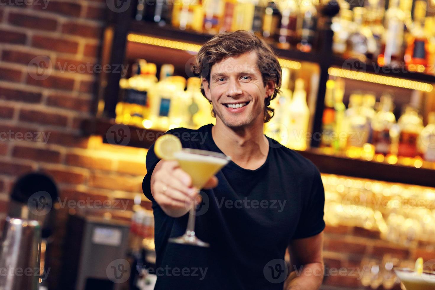 Gut aussehender Barkeeper, der Cocktails in einem Pub serviert foto