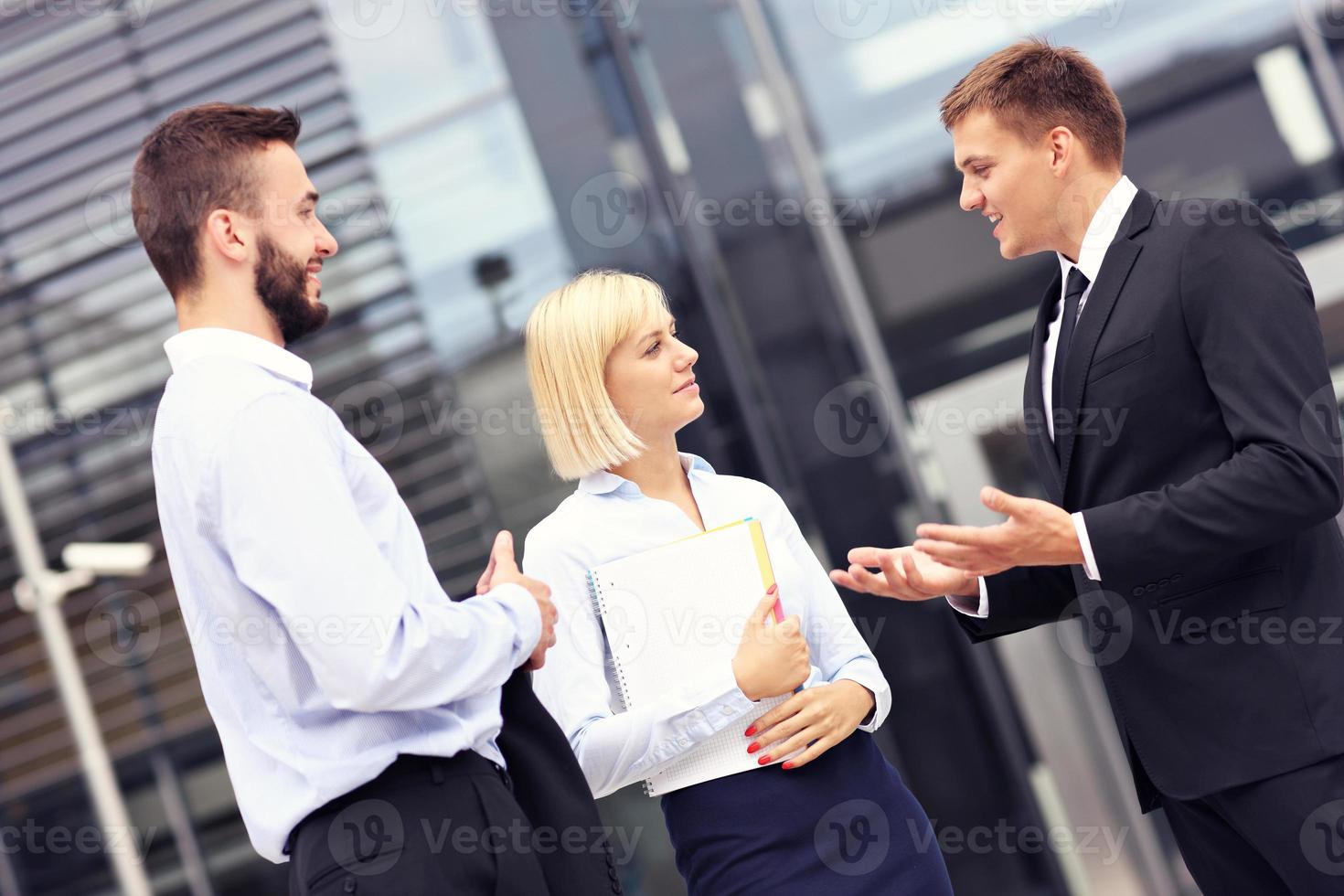 geschäftsleute, die außerhalb des modernen gebäudes diskutieren foto