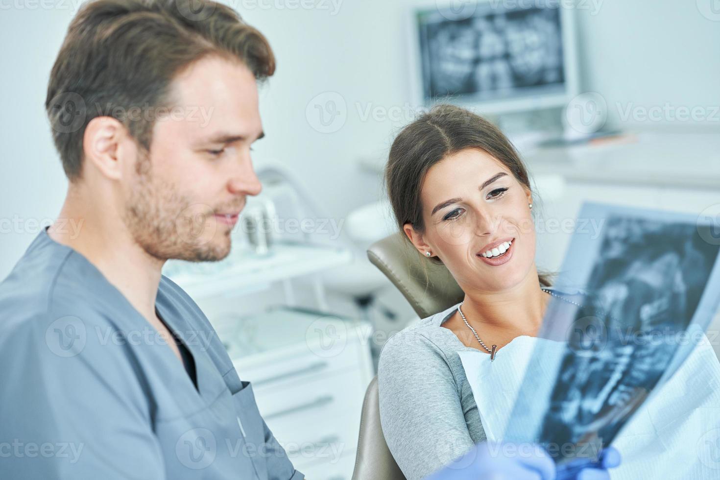 männlicher zahnarzt und frau diskutieren röntgenergebnisse in der zahnarztpraxis foto