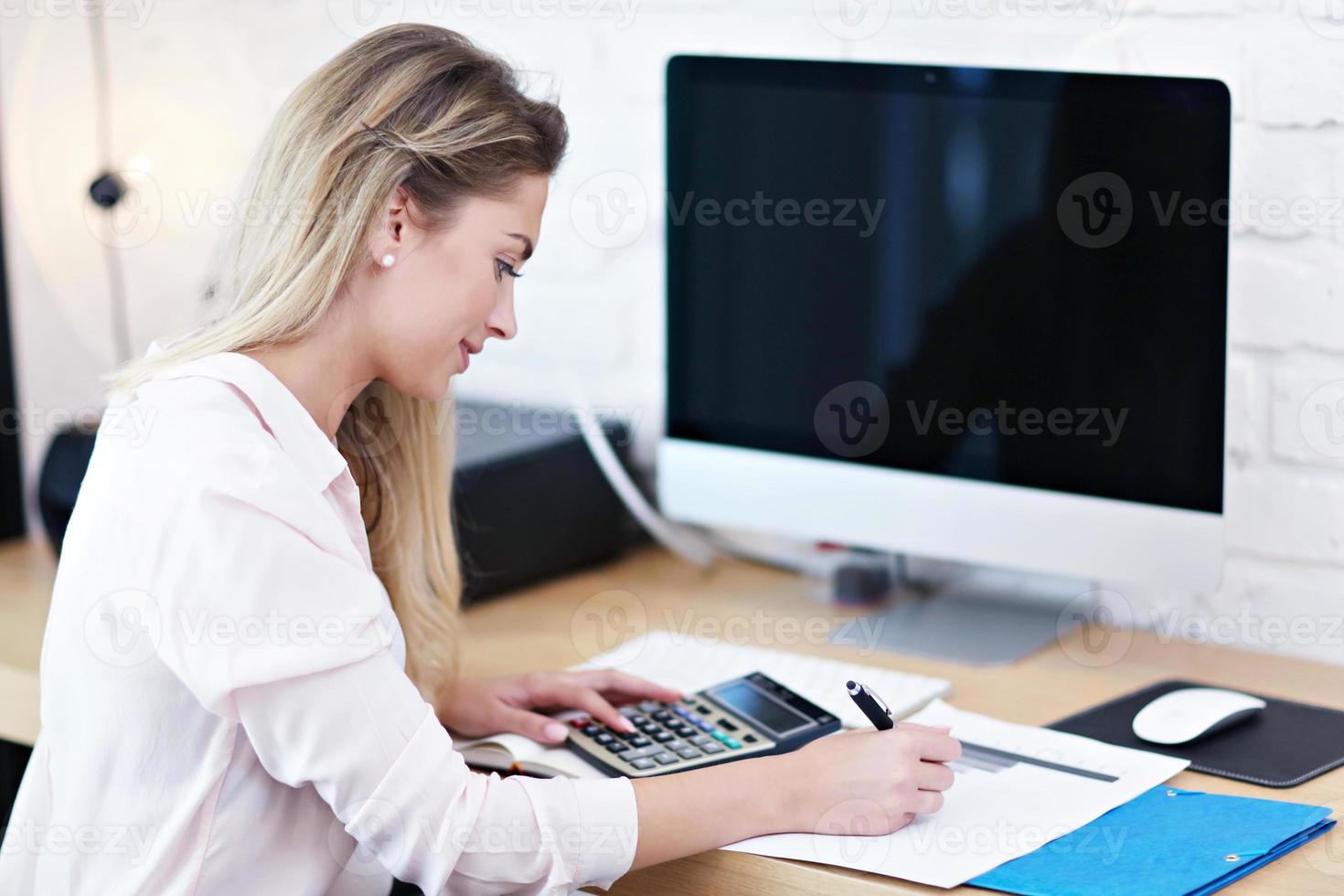 Porträt einer schönen tausendjährigen Frau, die im modernen Heimbüro arbeitet foto