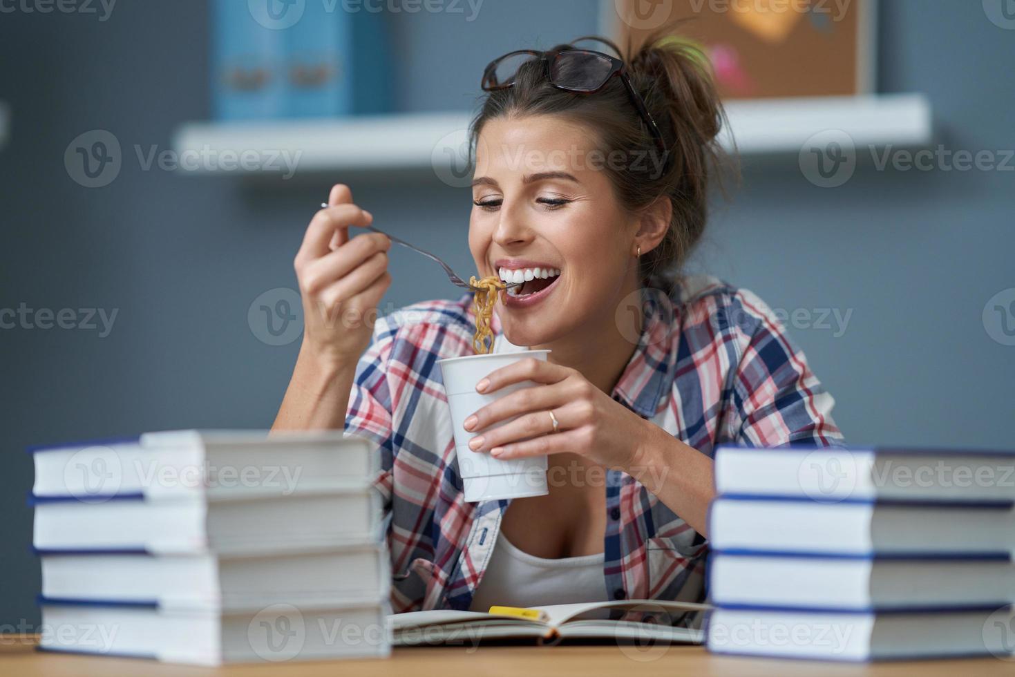 hungriger student, der nudeln isst, während er zu hause lernt foto