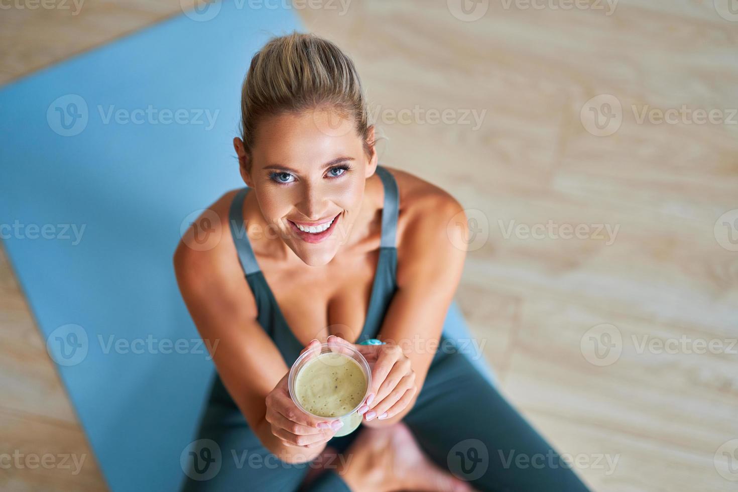 Erwachsene Frau, die nach dem Training gesunden Smoothie trinkt foto
