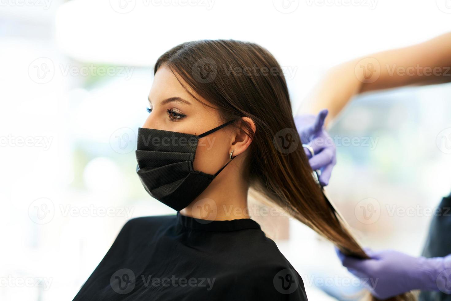 erwachsene frau beim friseur, die wegen einer coronavirus-pandemie eine schutzmaske trägt foto
