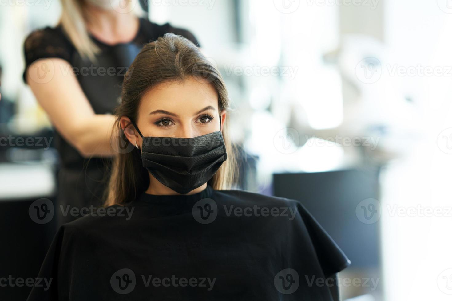 erwachsene frau beim friseur, die wegen einer coronavirus-pandemie eine schutzmaske trägt foto