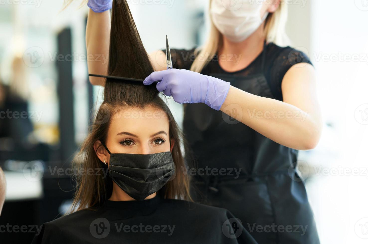 erwachsene frau beim friseur, die wegen einer coronavirus-pandemie eine schutzmaske trägt foto