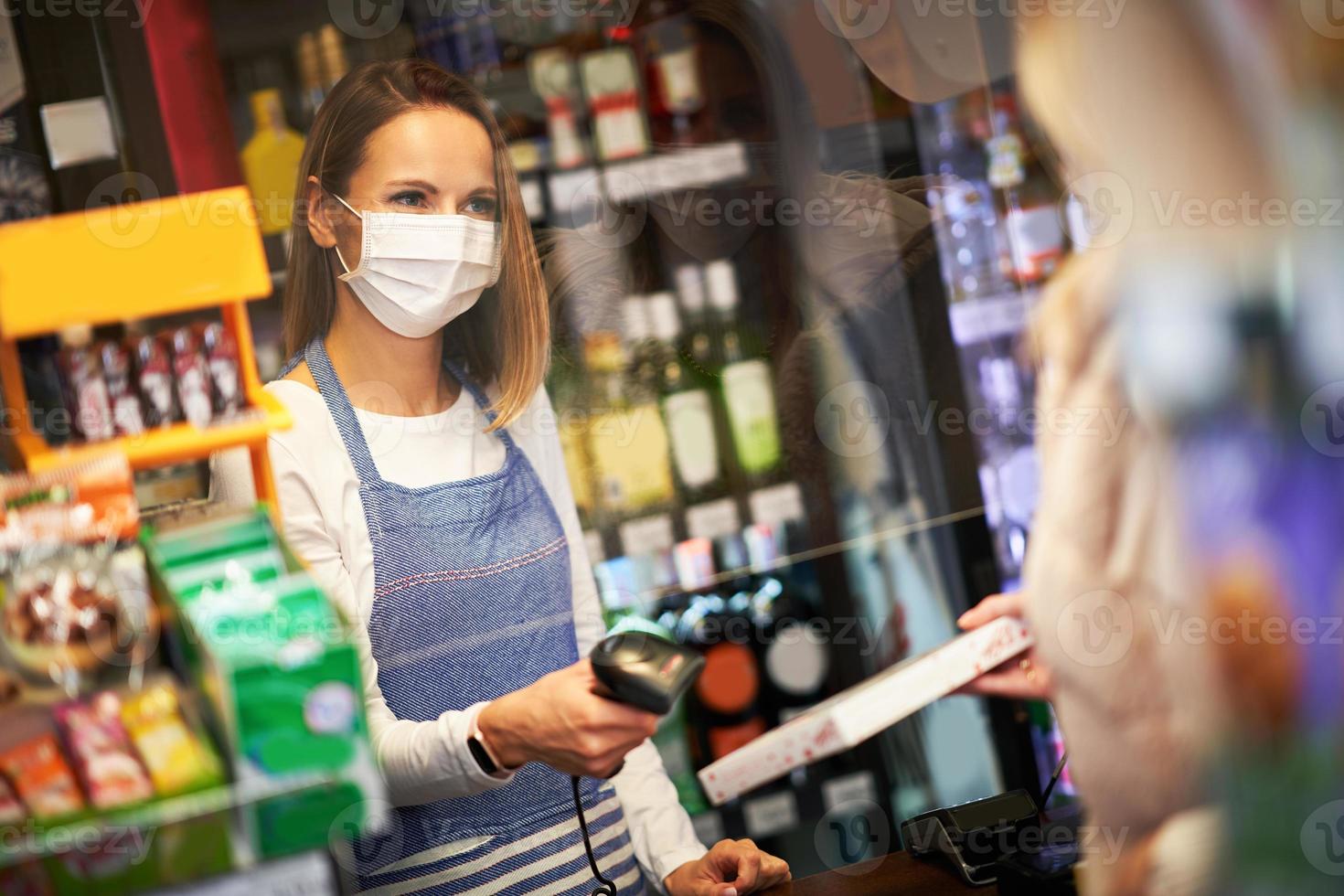 erwachsene Frau in medizinischer Maske, die Lebensmittel einkauft foto