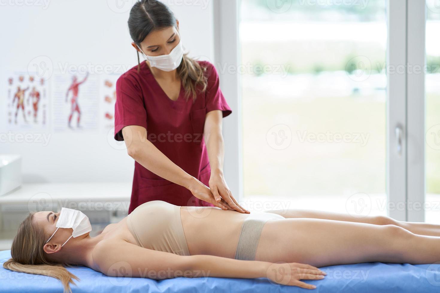 Physiotherapeut in Maske hilft Patientin foto