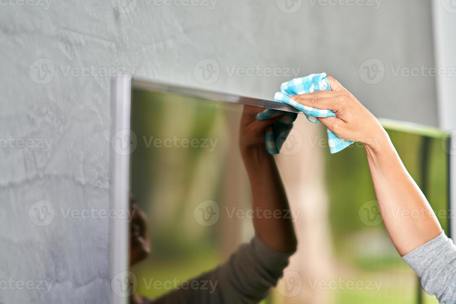 Bild einer jungen Frau, die den Fernsehbildschirm reinigt foto