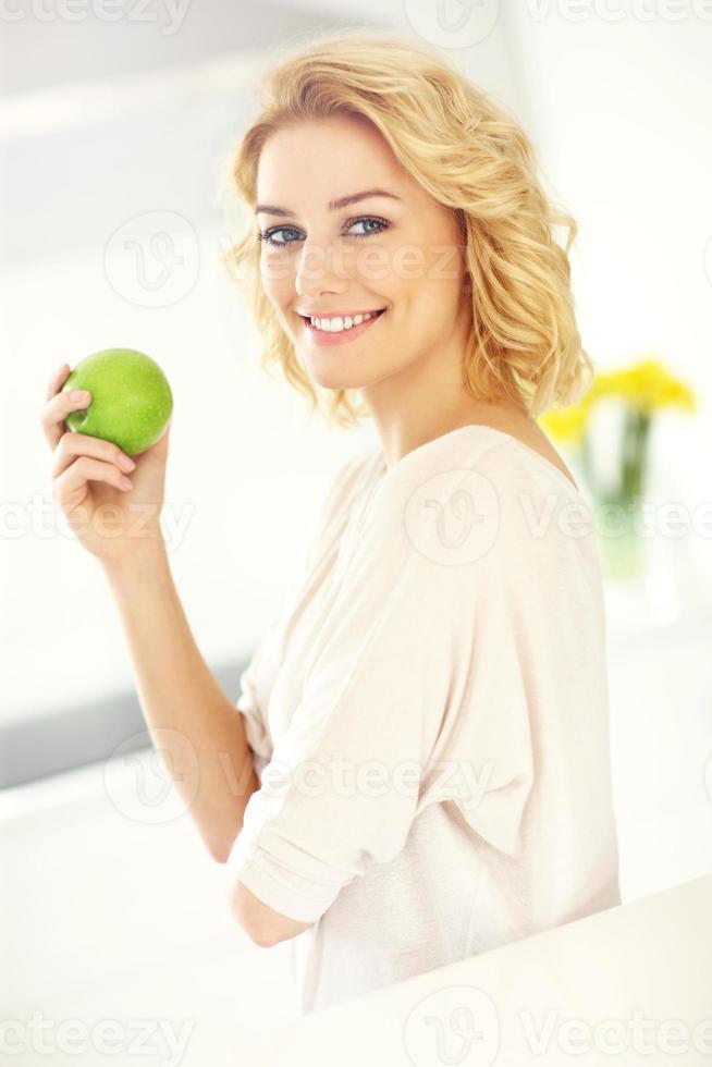 junge frau, die apfel in der küche isst foto