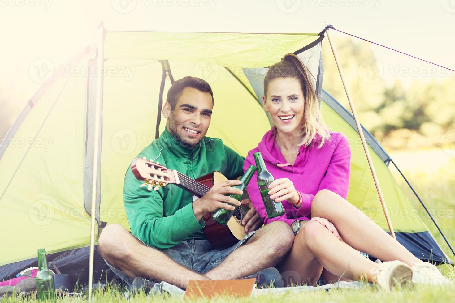 Paar Camping im Wald und Gitarre spielen foto