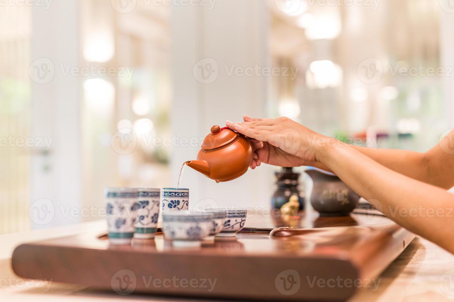 tee wird in die tasse nahaufnahme gegossen. asiatischer tee auf hölzernem bambustisch, chinesischer tee wird von hand sanft gegossen foto