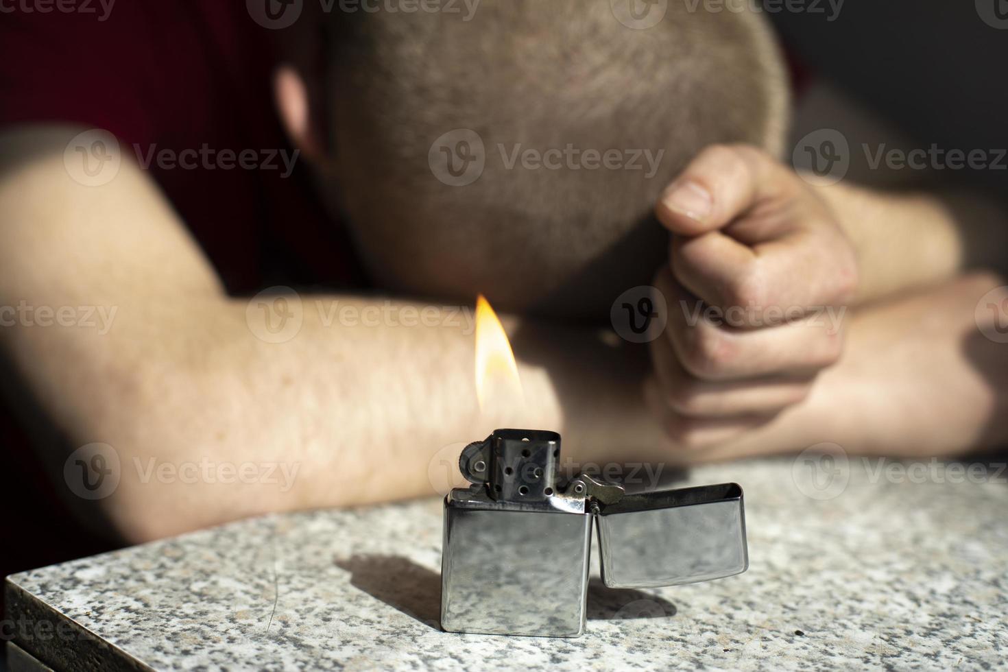 Benzinfeuerzeug brennt auf dem Tisch. Feuer im Hintergrund des schlafenden Kerls. Parteidetails. foto
