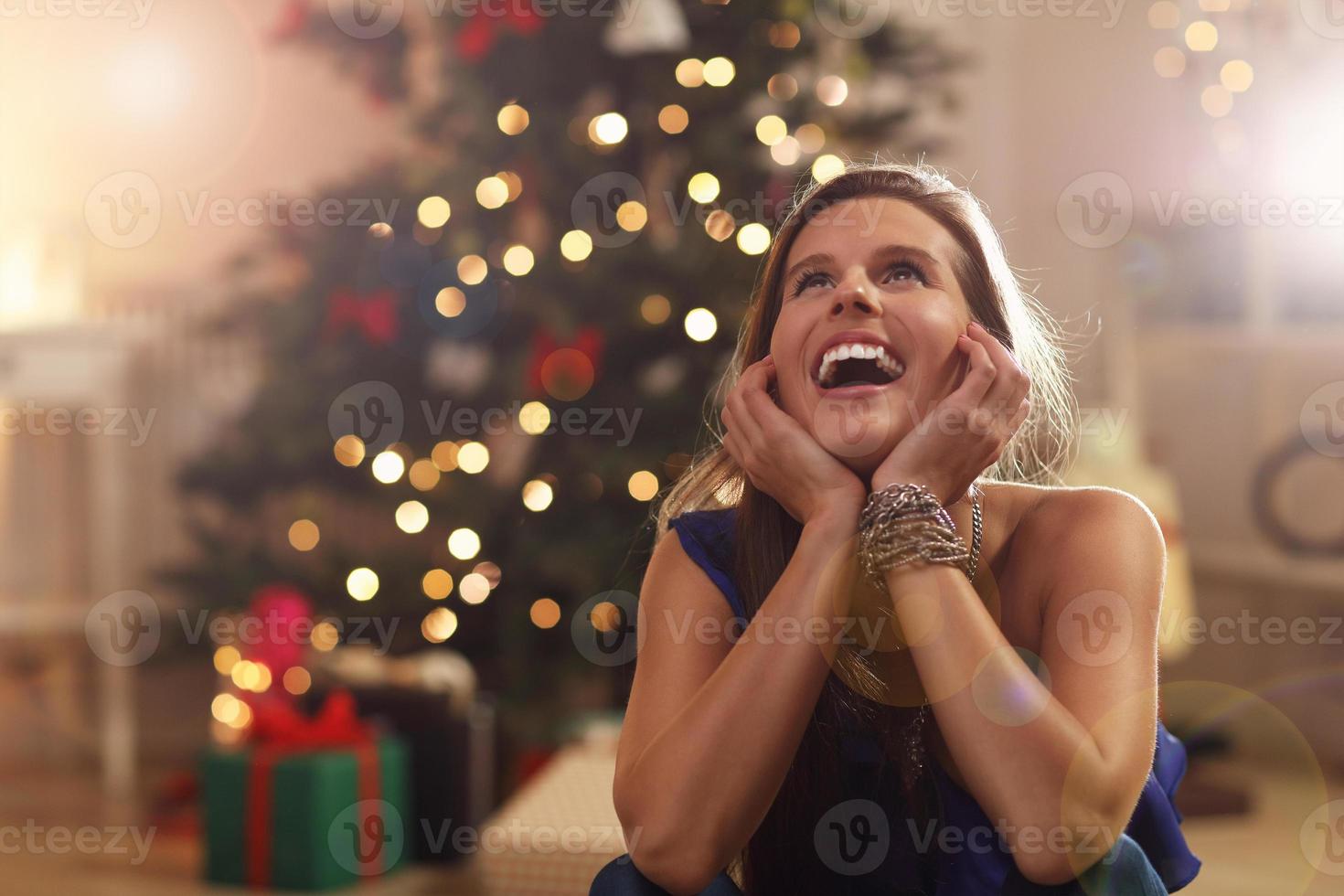 glückliche frau, die über weihnachtsbaum sitzt foto