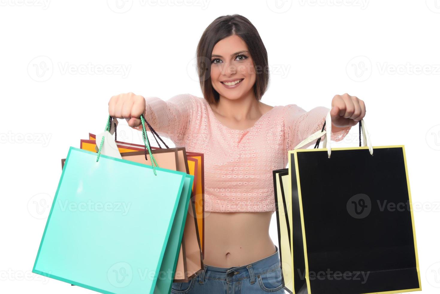 Bild einer schönen jungen Brunettedame, die mit Einkaufstaschen aufwirft und Kamera betrachtet. Einkaufskonzept. isoliert foto