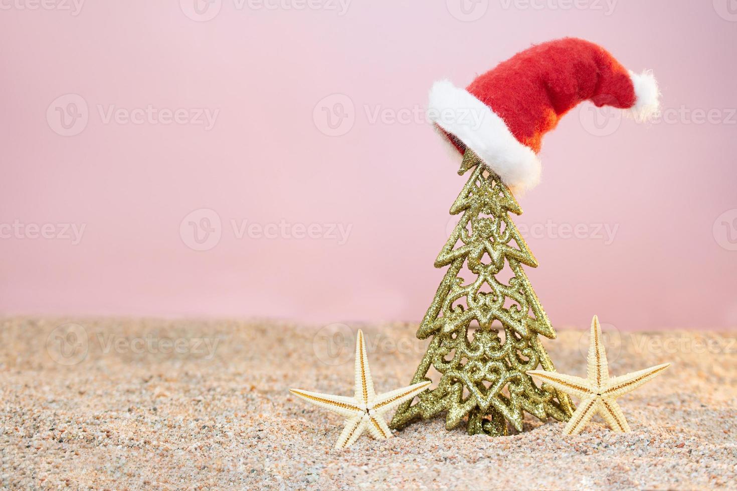 goldener weihnachtsbaum mit weihnachtsmütze und seesternen auf sand. weihnachten, neujahr. Platz kopieren foto