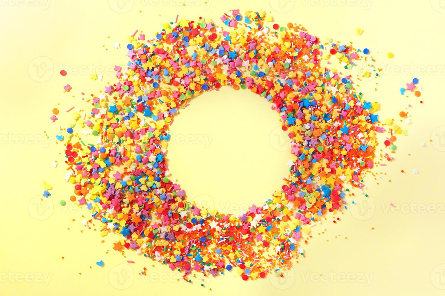 süßes Konfetti in der Mitte eines Kreises mit leerem Platz für Text. gelber Hintergrund foto