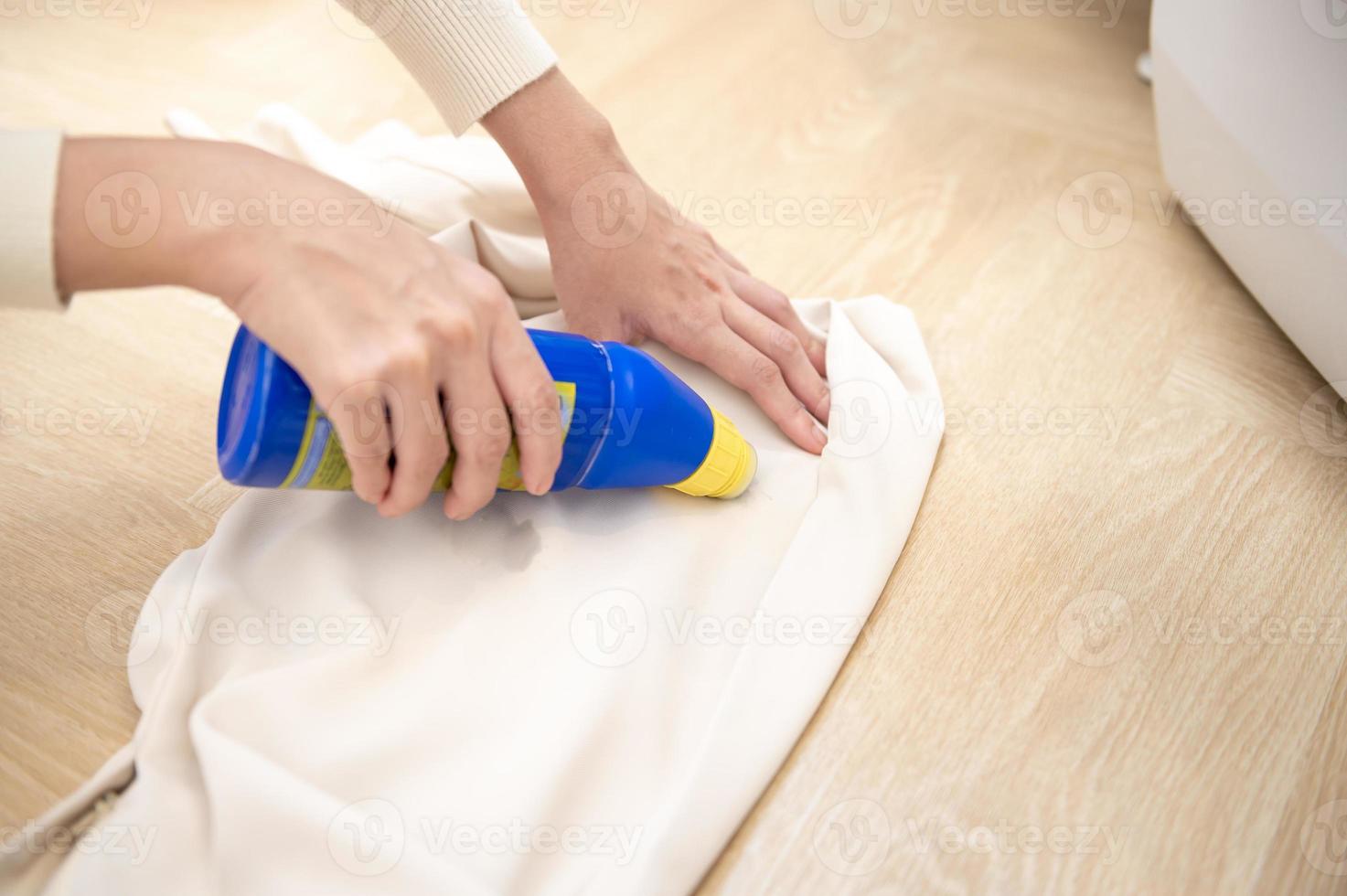 Nahaufnahme der weiblichen Hand, die Reinigungsmittel aufträgt, um schwere Flecken in der Kleidung zu entfernen foto