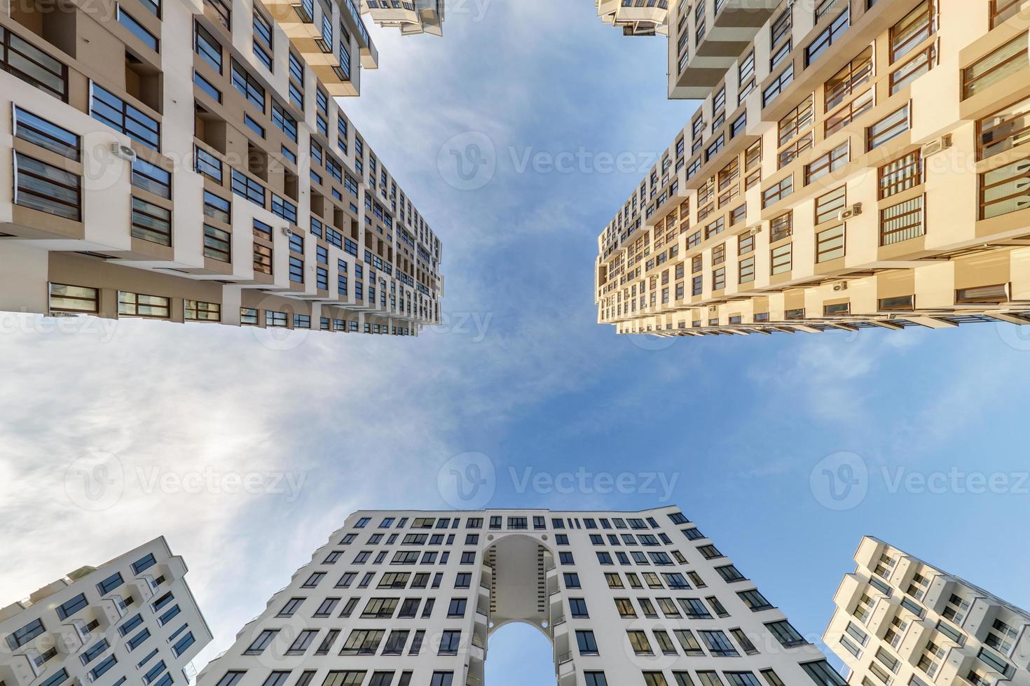 Blick vom Boden zum blauen Himmel zwischen Wolkenkratzern, Blick auf das Haus von unten nach oben foto