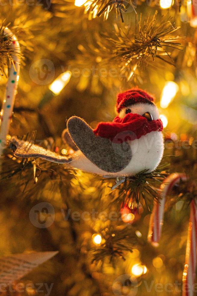 Vogelweihnachtsverzierung, die an einem Weihnachtsbaum mit weichen Lichtern hängt foto