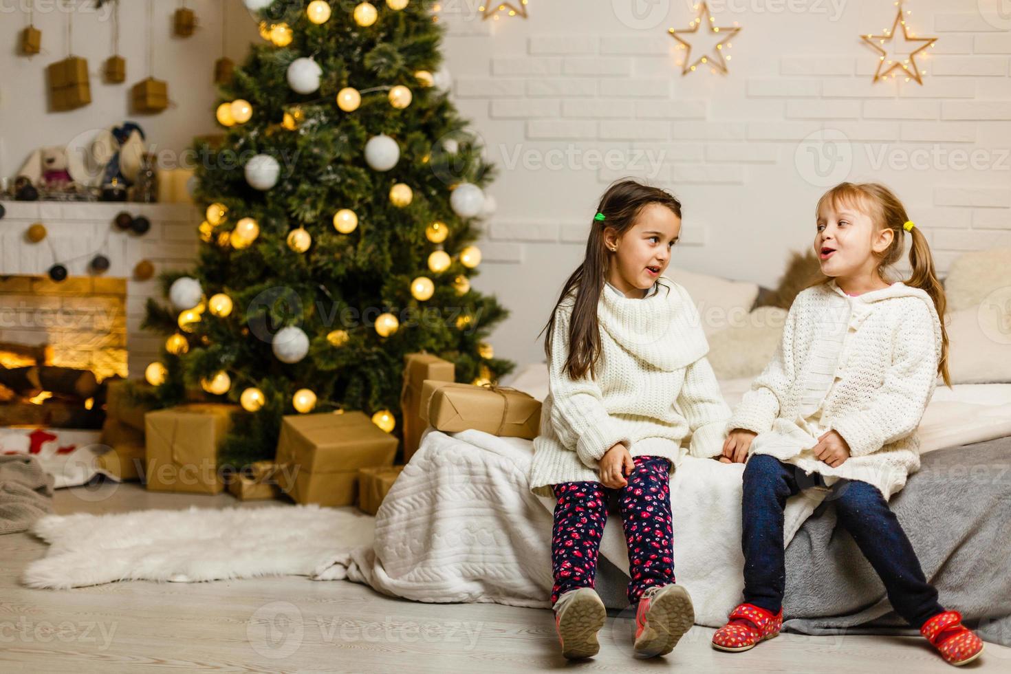 Zwei kleine Mädchen teilen sich am Weihnachtsmorgen eine Überraschung foto