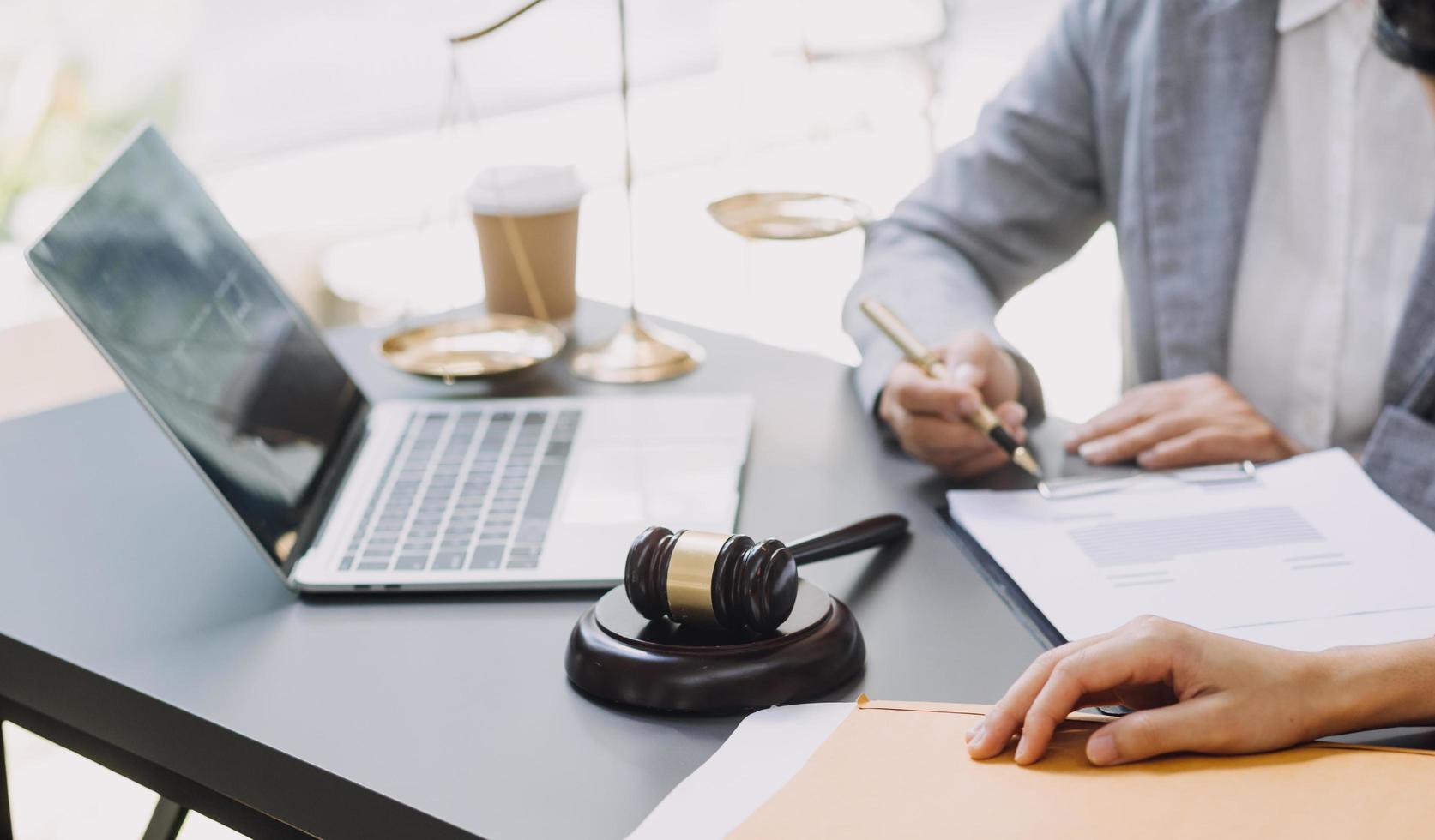 geschäftsleute und anwälte diskutieren vertragspapiere mit messingwaage auf dem schreibtisch im büro. gesetz, juristische dienstleistungen, beratung, justiz und gesetz konzeptbild mit filmkorneffekt foto