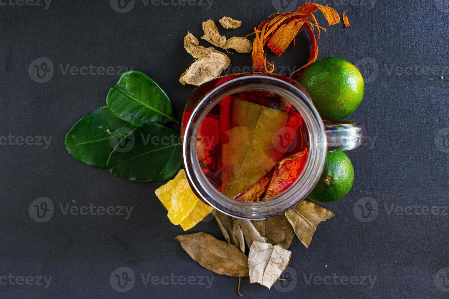 Wedang Uwuh ist ein traditionelles Kräutergetränk aus Indonesien. aus Zimt, Muskatnuss und Nelkenblättern. eine weitere zutat ist holz vom secangbaum, ingwer und würfelzucker auf schwarzem hintergrund foto