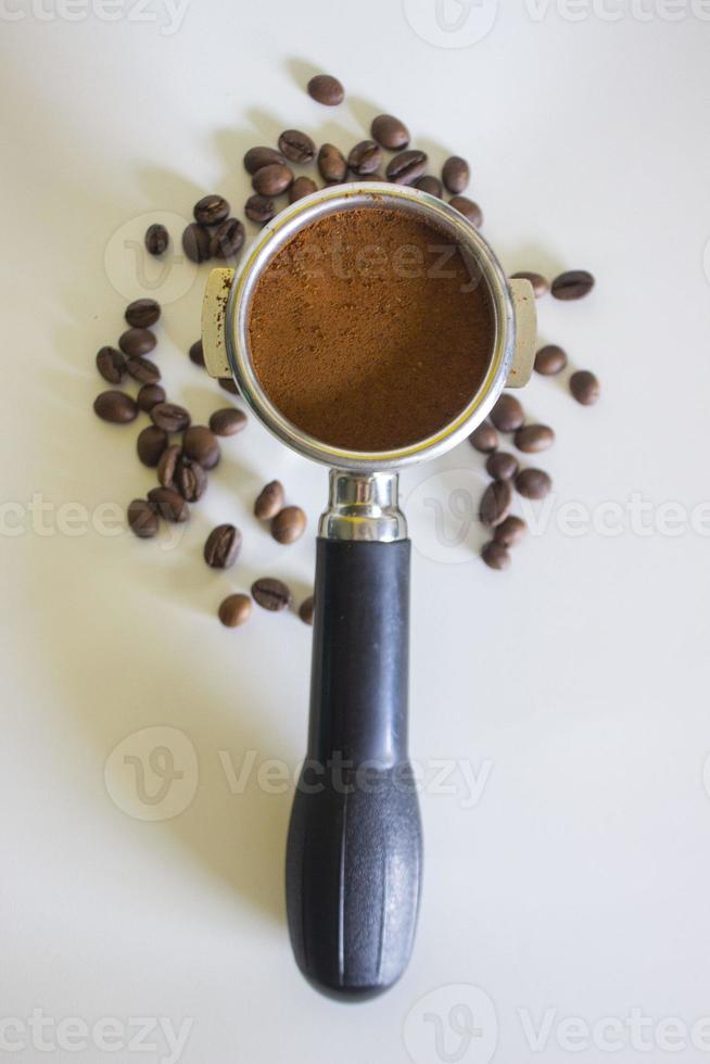Porta-Filter mit gemahlenem Kaffee und Kaffeebohne isoliert von einem weißen Hintergrund foto