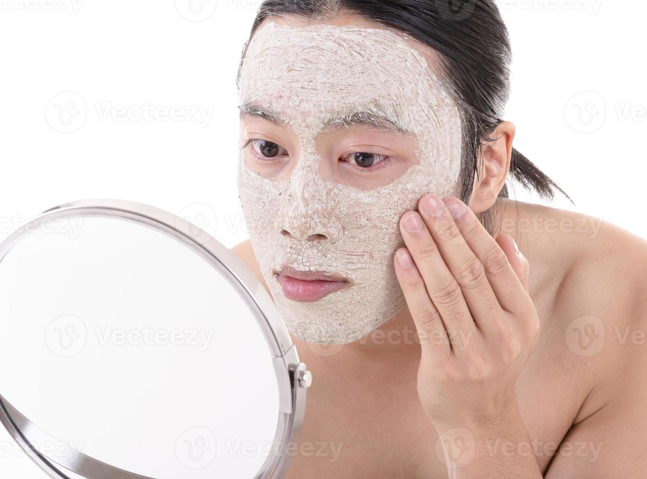 Schönheitsverfahren und Hautpflege. Nahaufnahme Porträt eines glücklich lachenden, oben ohne asiatischen Mannes mit Gesichtsmaske, die sein Gesicht berührt. isoliert auf weißem Hintergrund. foto