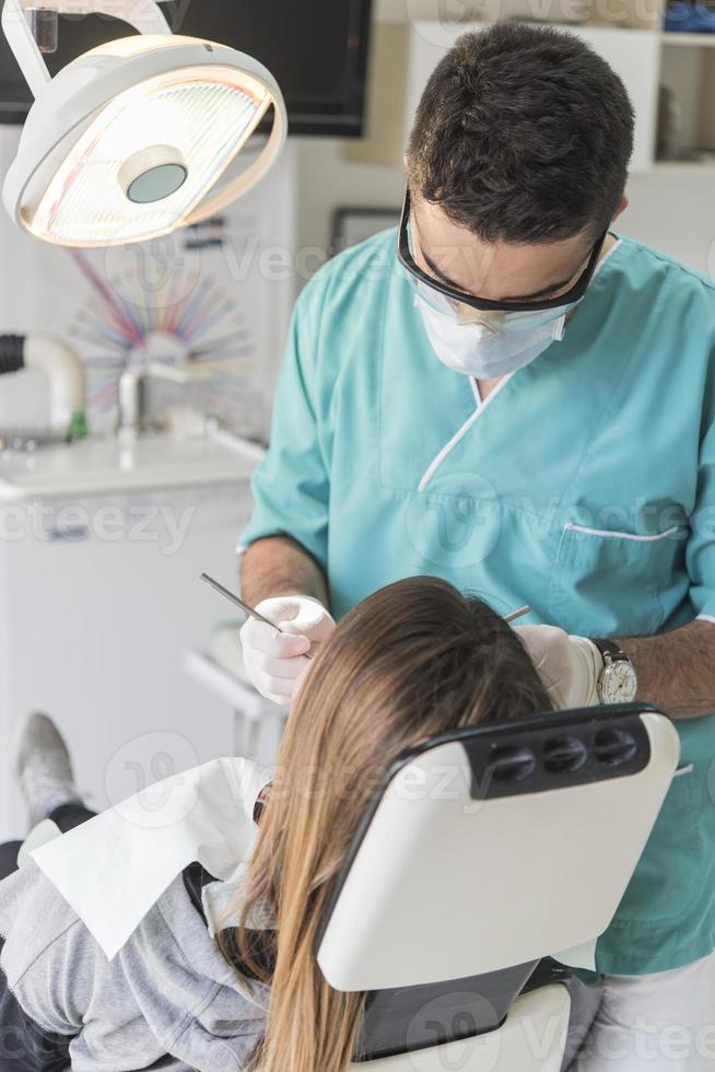 Zahnarzt heilt die Zähne des Patienten und füllt den Hohlraum. zahnarzt, der mit professioneller ausrüstung in der klinik arbeitet. foto