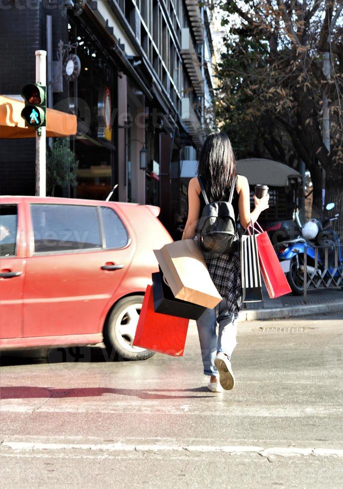 schöne frau, die mit einkaufstüten auf der straße geht. trendiges weibliches modell in der stadt, das einkaufstaschen hält. foto