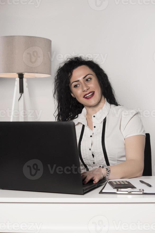 glückliche Geschäftsfrau, die versucht, in ihrem Büro zu arbeiten foto