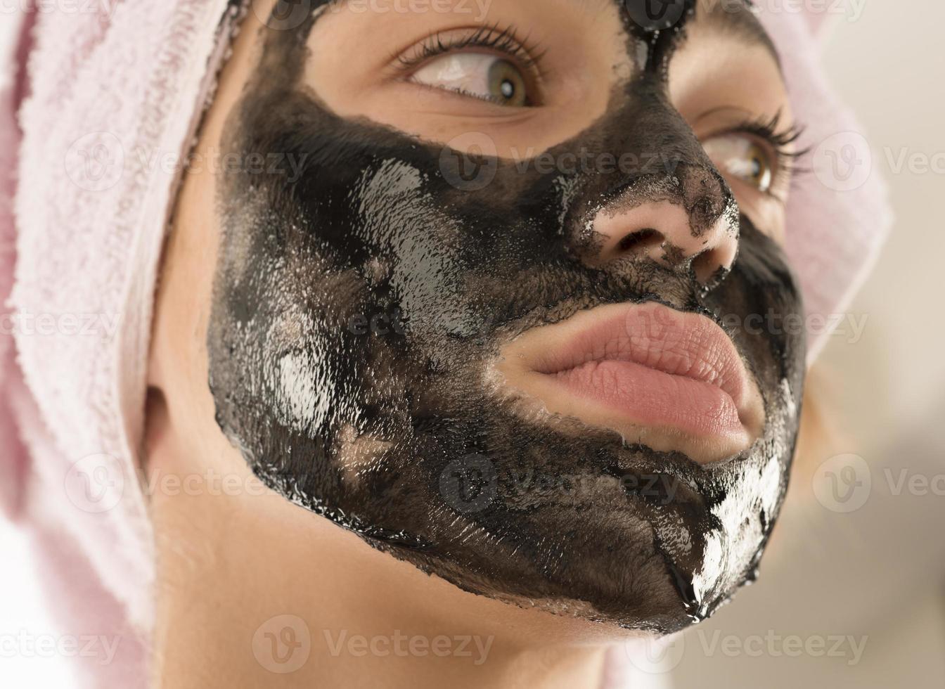 schwarze Gesichtsmaske. schönes Mädchen mit schwarzer Kosmetikmaske im Gesicht. Beauty-Konzept foto