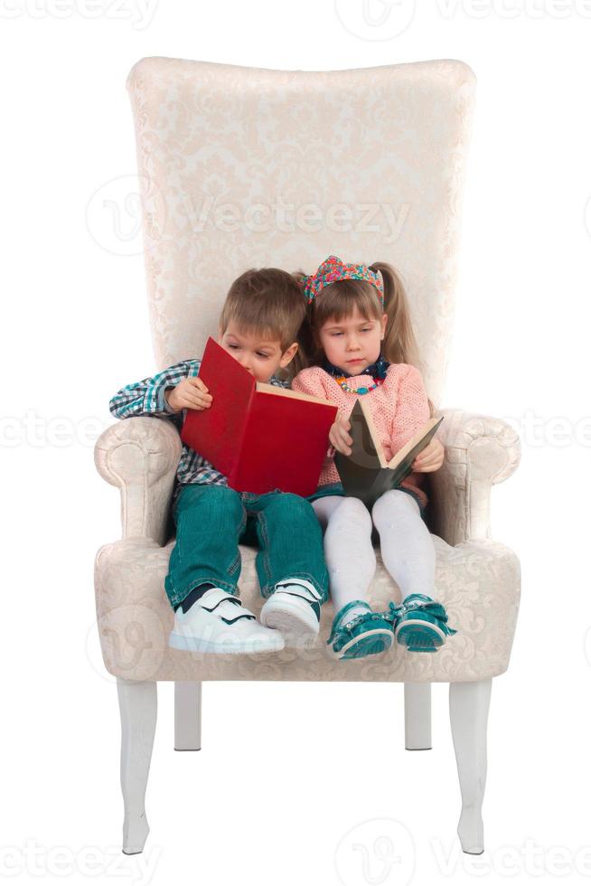 Kinder sitzen mit Büchern auf einem Stuhl foto