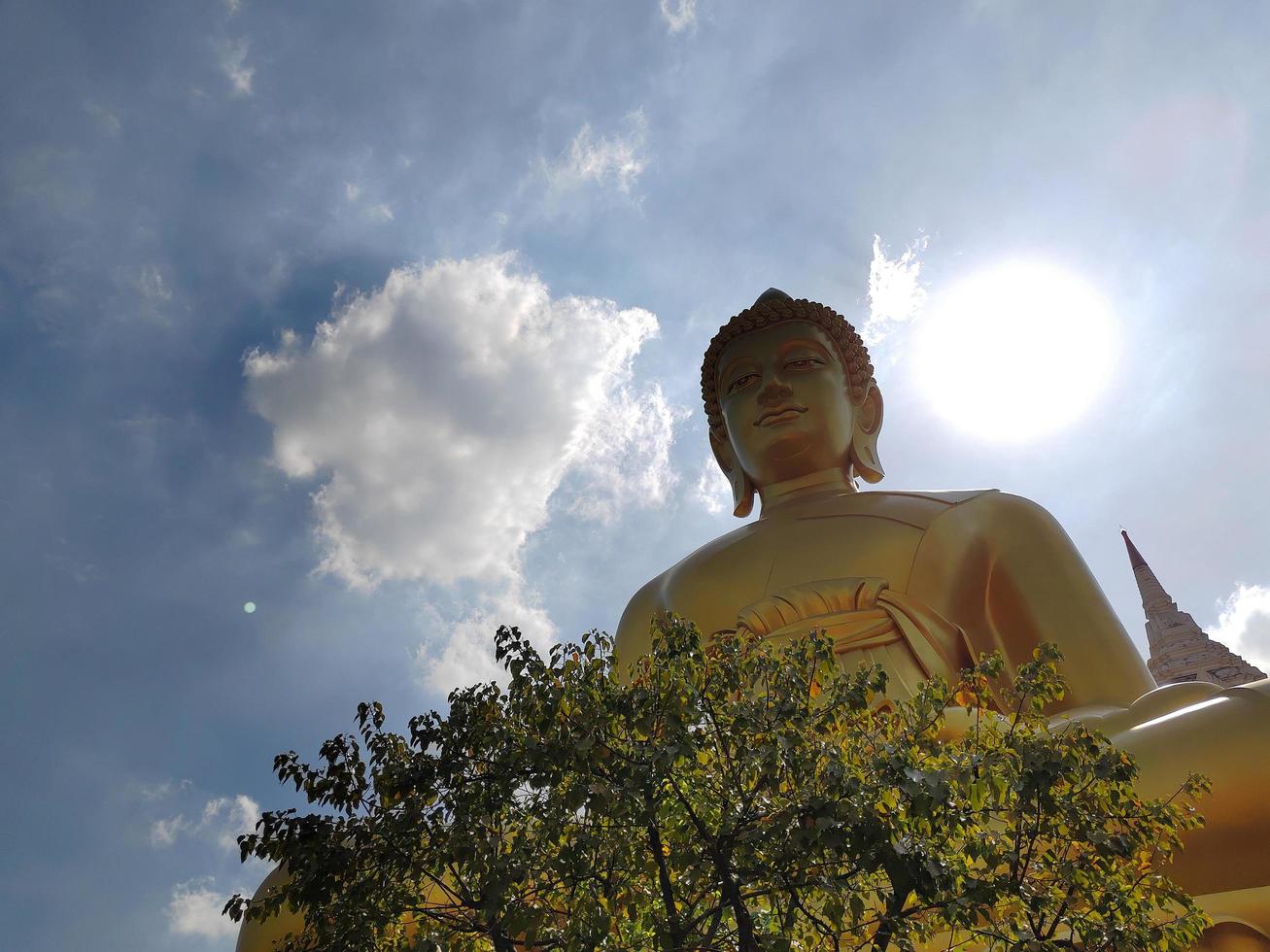 goldene große buddha-statue phra buddha dhammakaya thep mongkol im wat pak nam phasi charoen tempel. sonnenlicht, himmel und wolkenhintergrund foto