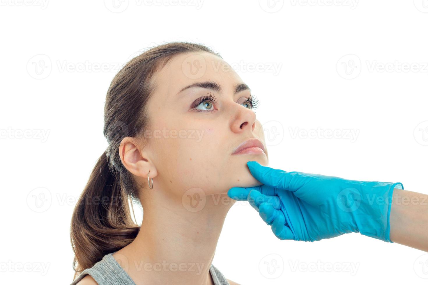 horizontales Porträt eines jungen Mädchens, das seinen Kopf auf die behandschuhte Hand des Arztes hebt foto