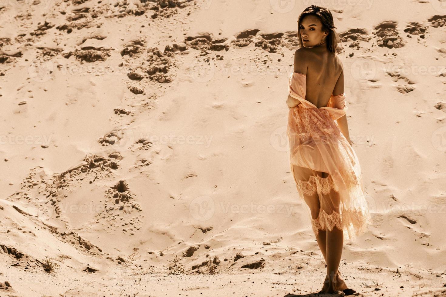 junges sexy Mädchen im rosafarbenen Kleid in der Wüste foto