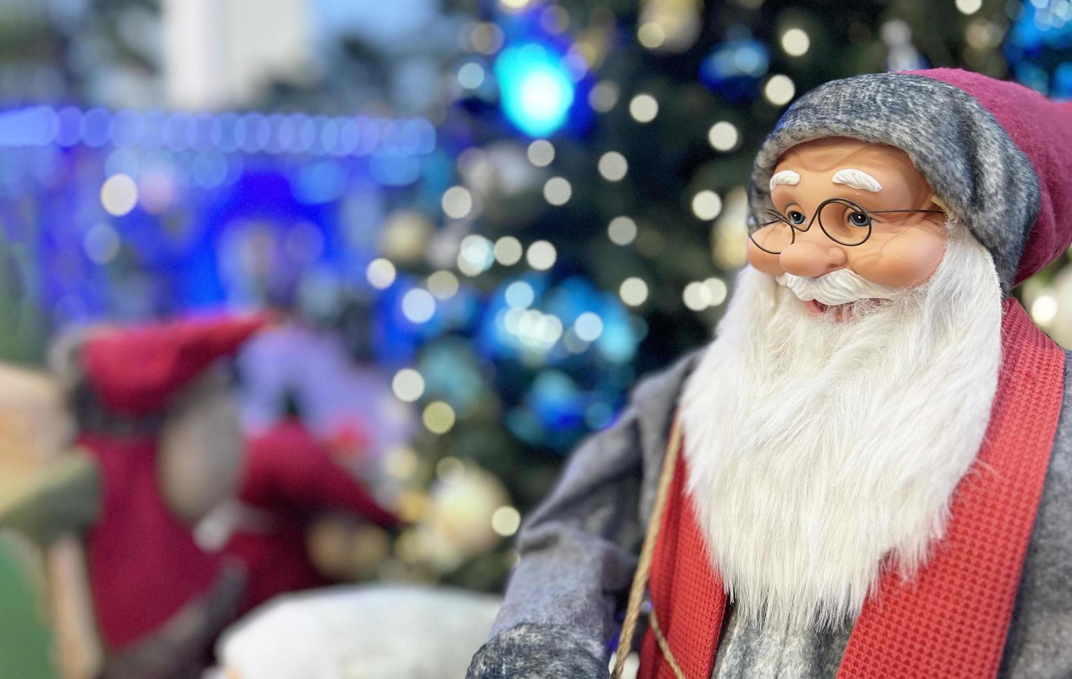 glückliche weihnachtsmannpuppe, die auf weihnachtsbaumhintergrund lächelt foto