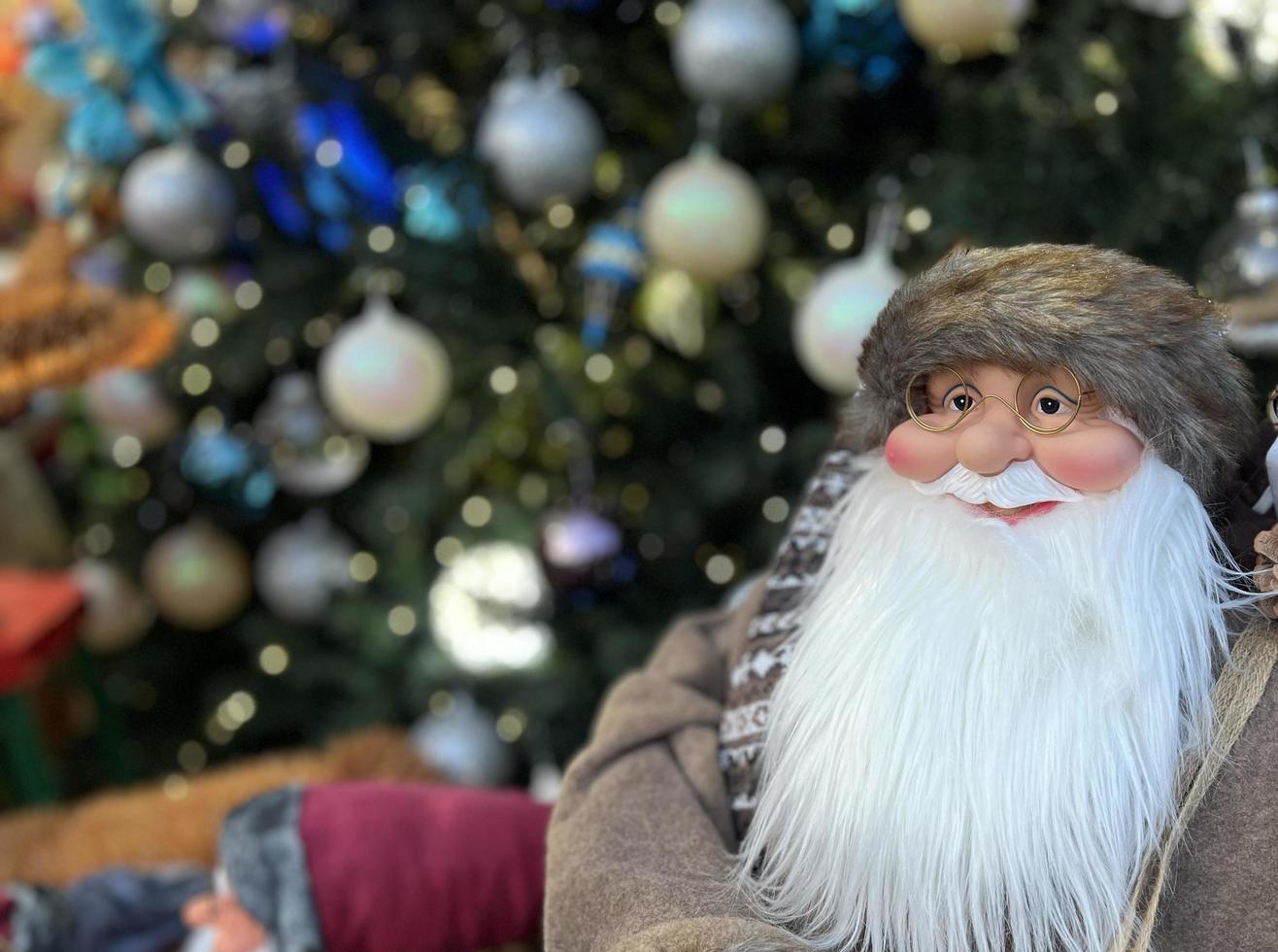 glückliche weihnachtsmannpuppe, die auf weihnachtsbaumhintergrund lächelt foto