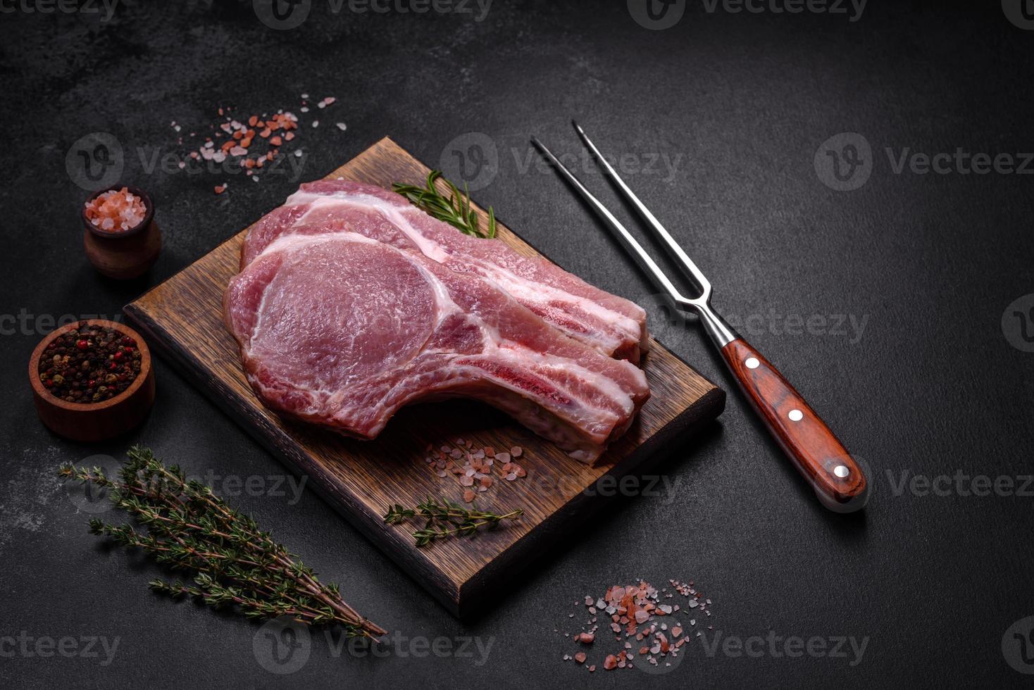 frisches rohes Schweinefleisch auf den Rippen mit Gewürzen und Kräutern auf einem Holzschneidebrett foto