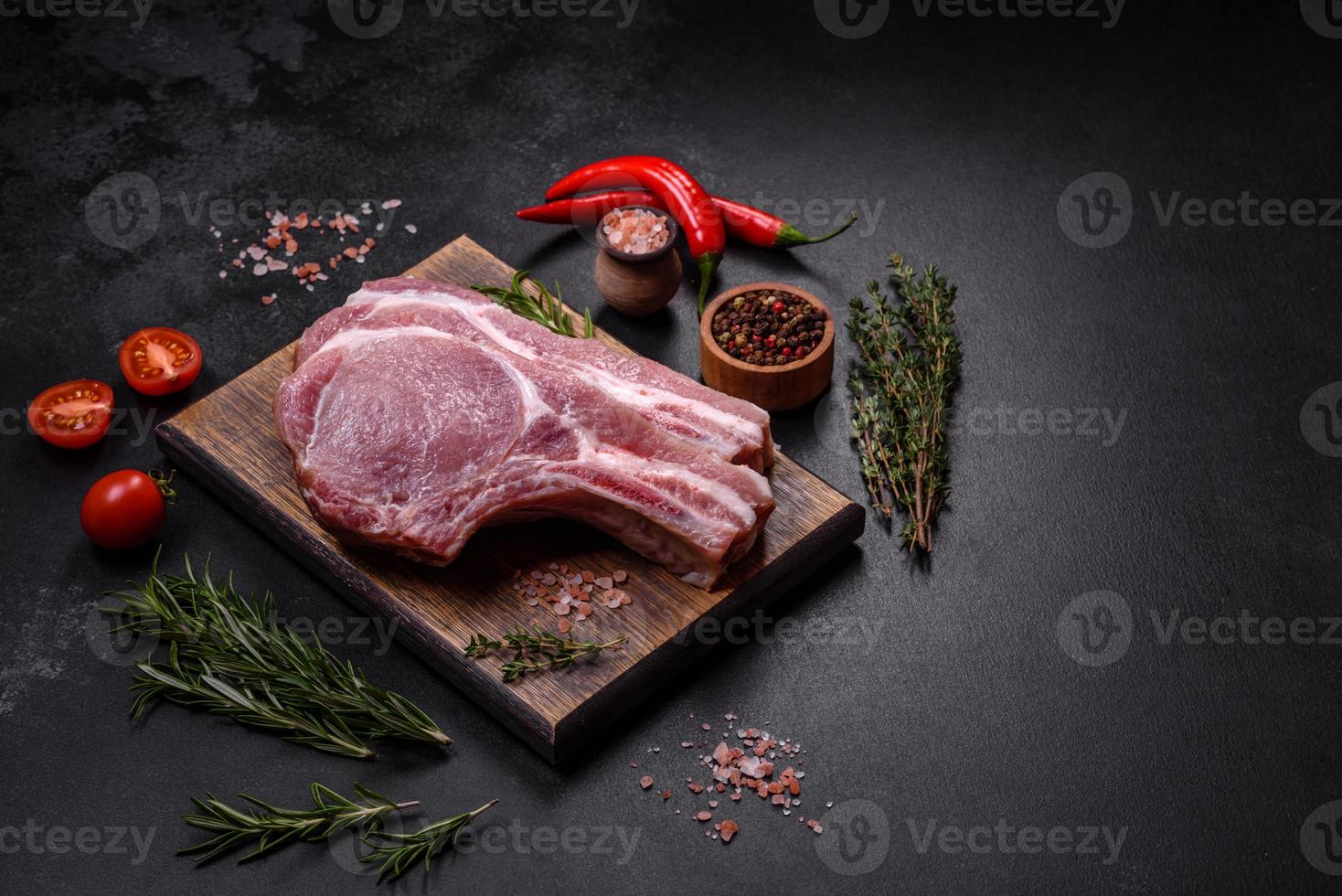 frisches rohes Schweinefleisch auf den Rippen mit Gewürzen und Kräutern auf einem Holzschneidebrett foto