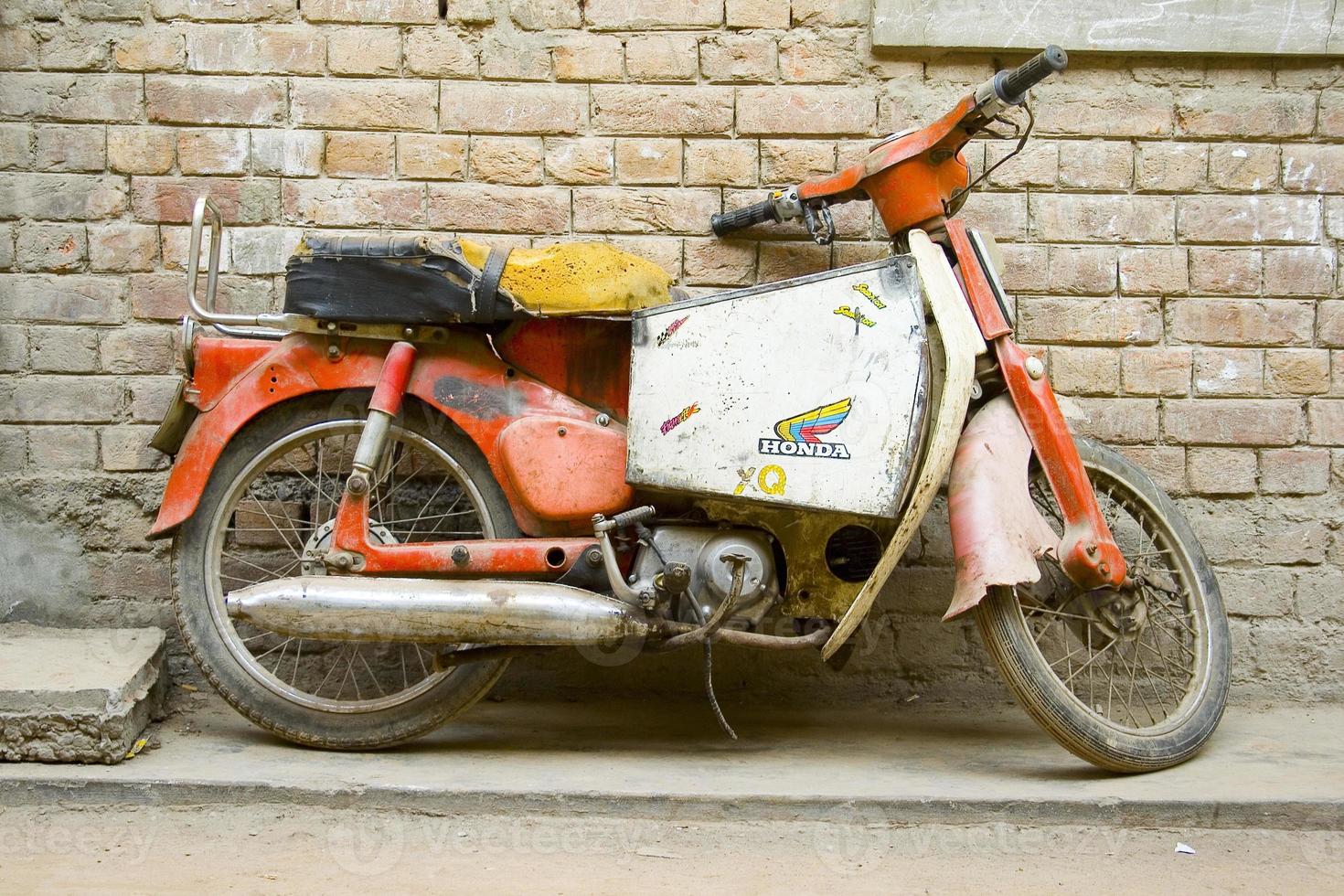 Altes Motorrad, das an einer Mauer geparkt ist foto