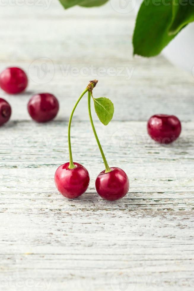 zwei rote Kirsche mit Blatt auf weißem Hintergrund foto