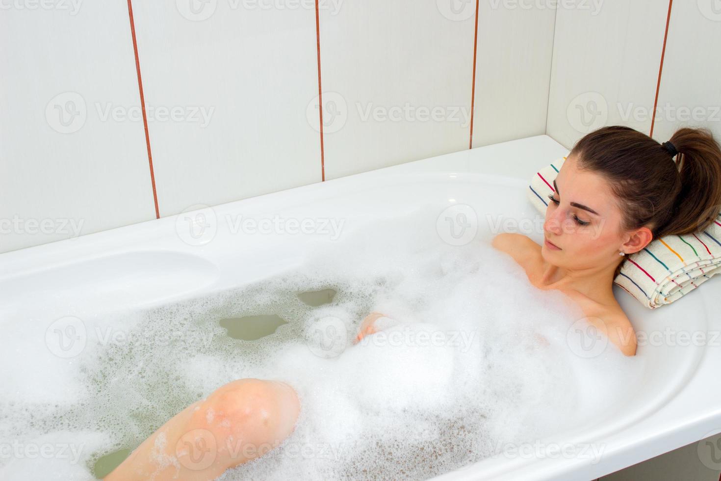 junges Mädchen liegt in heißem Wasser im Bad mit Schaum foto
