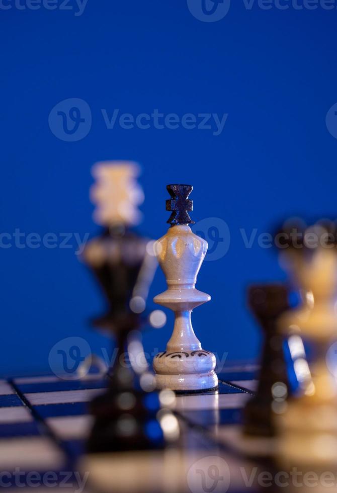 Schachbrett mit Schachfiguren auf blauem Hintergrund. konzept von geschäftsideen und wettbewerbs- und strategieideen. Weiße und schwarze Könige aus nächster Nähe. foto